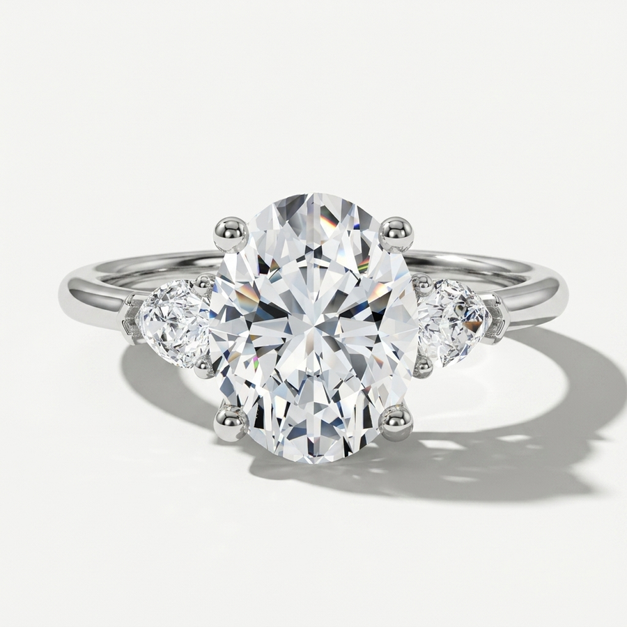 Three stone engagement ring with oval center diamond and pear side stones