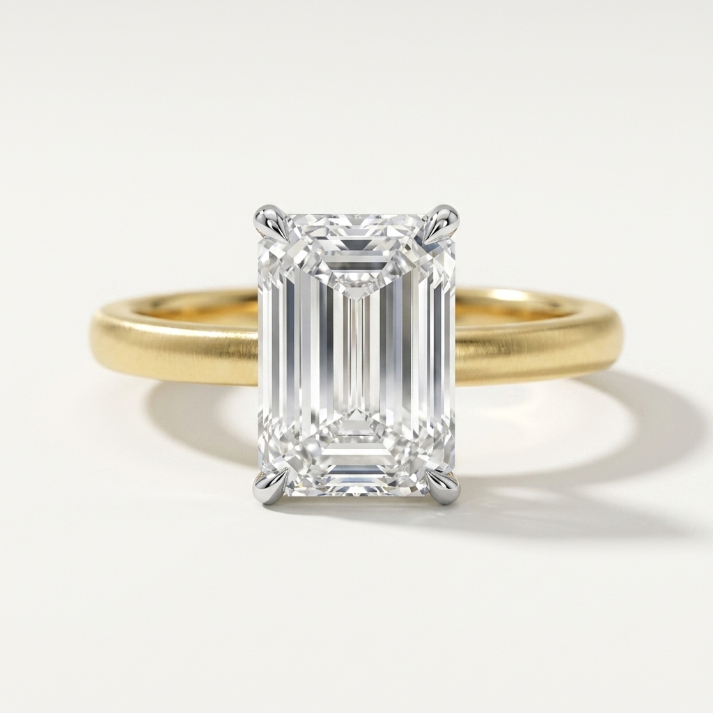 An emerald-cut diamond engagement ring with a yellow gold band, photographed on a clean white background.