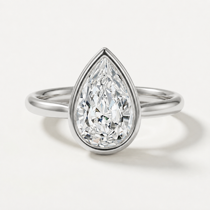 A pear-cut diamond ring in a white gold setting with a polished band, shown on a clean white background.