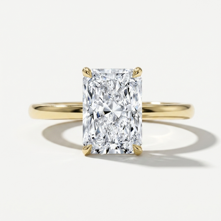 Elongated radiant cut diamond solitaire engagement ring on a petite yellow gold band