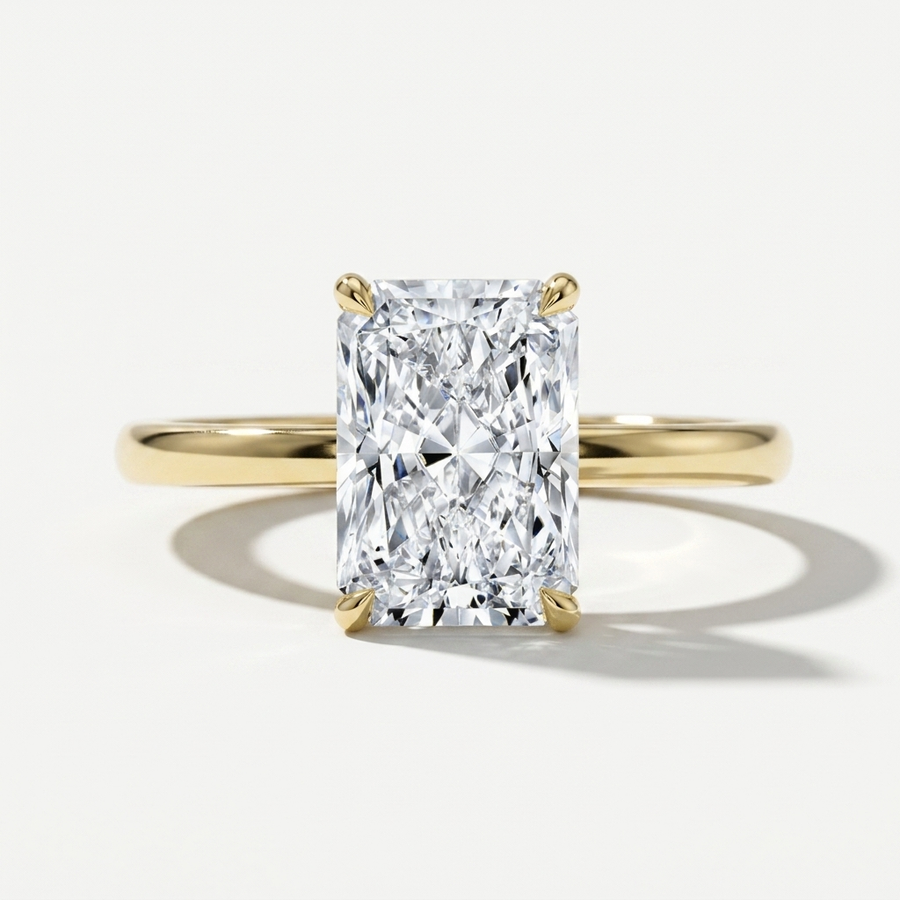 Elongated radiant cut diamond solitaire engagement ring on a petite yellow gold band