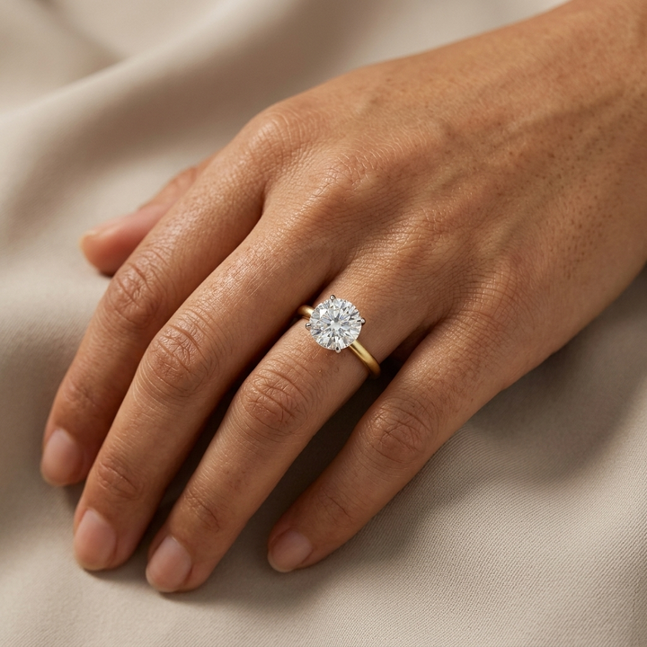 Round Diamond set in a 4 Prong two tone gold solitaire mounting on a woman's hand
