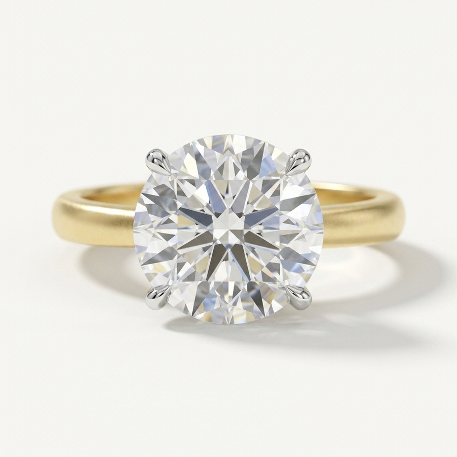 A classic solitaire engagement ring featuring a round brilliant-cut diamond set in a yellow gold band with a four-prong setting, photographed on a clean white background.