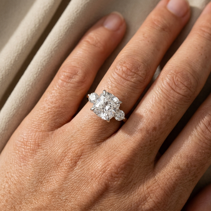 Cushion and round three stone 14kt two tone engagement ring on woman's hand