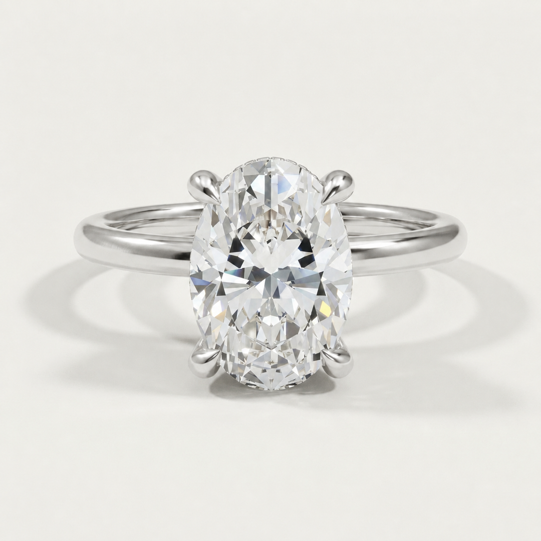 An oval-cut diamond engagement ring with diamond hidden halo set in a white gold  band, shown on a clean, light gray background.