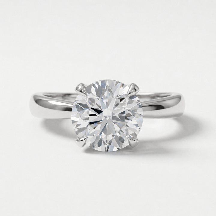 A classic solitaire engagement ring featuring a round brilliant-cut diamond set in a polished white gold metal band, shown against a clean white background.