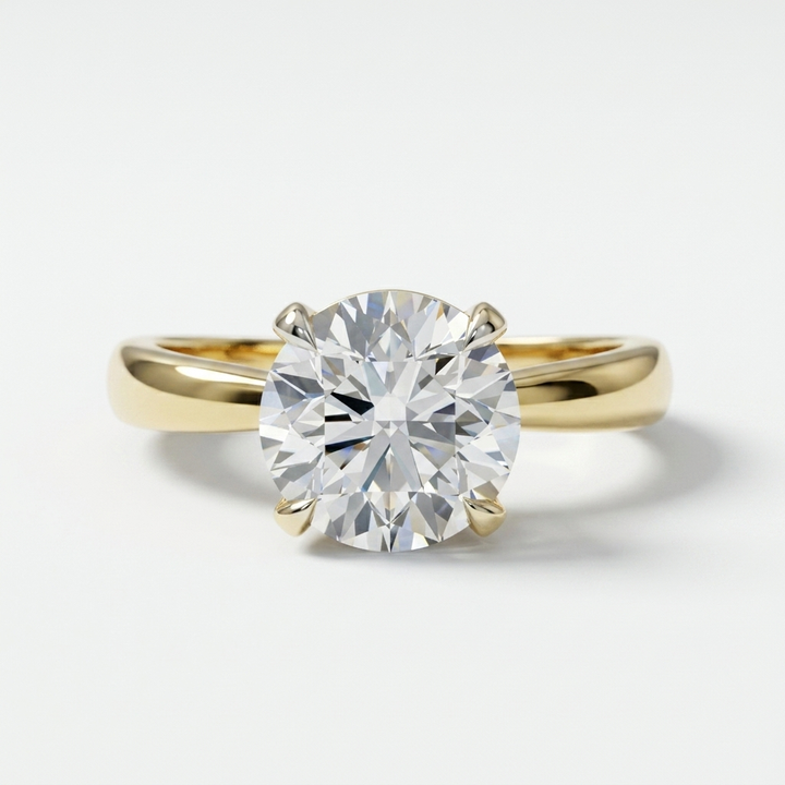 A classic solitaire engagement ring featuring a round brilliant-cut diamond set in a yellow gold four-prong pinched band, photographed on a clean white background.
