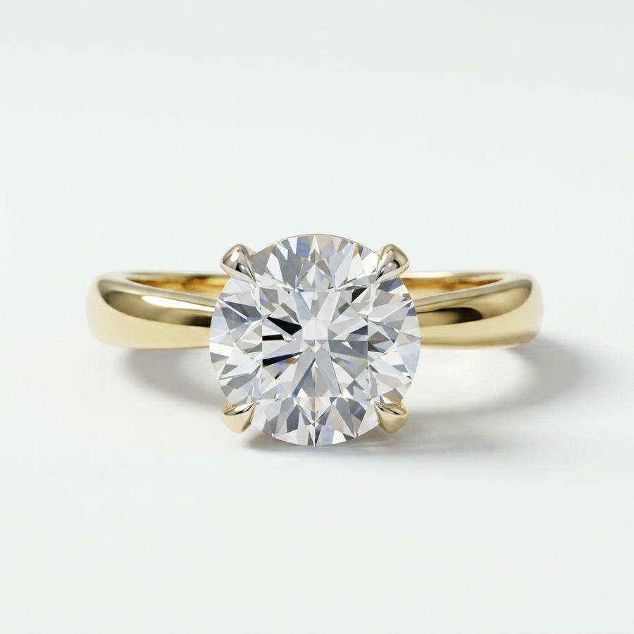 A classic solitaire engagement ring featuring a round brilliant-cut diamond set in a yellow gold four-prong pinched band, photographed on a clean white background.