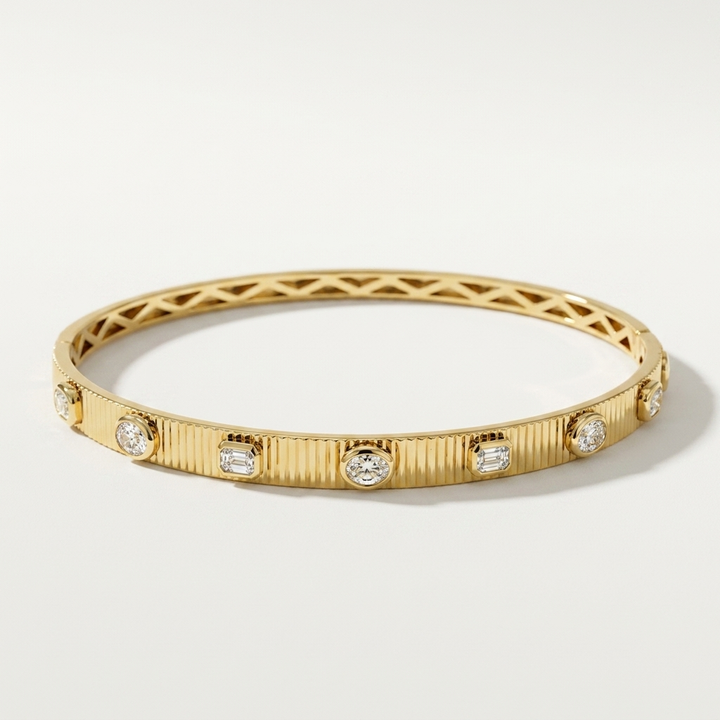 Refined 3.85ctw oval-cut lab grown emerald and diamond bangle in yellow gold, a sleek and sophisticated accessory for any occasion