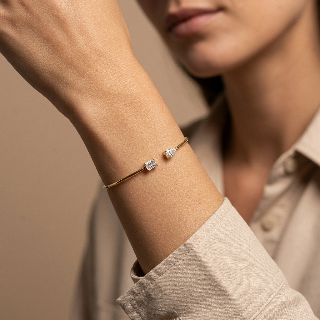 Refined pear-shaped lab grown emerald and diamond bangle in yellow gold, a sleek and sophisticated accessory for any occasion