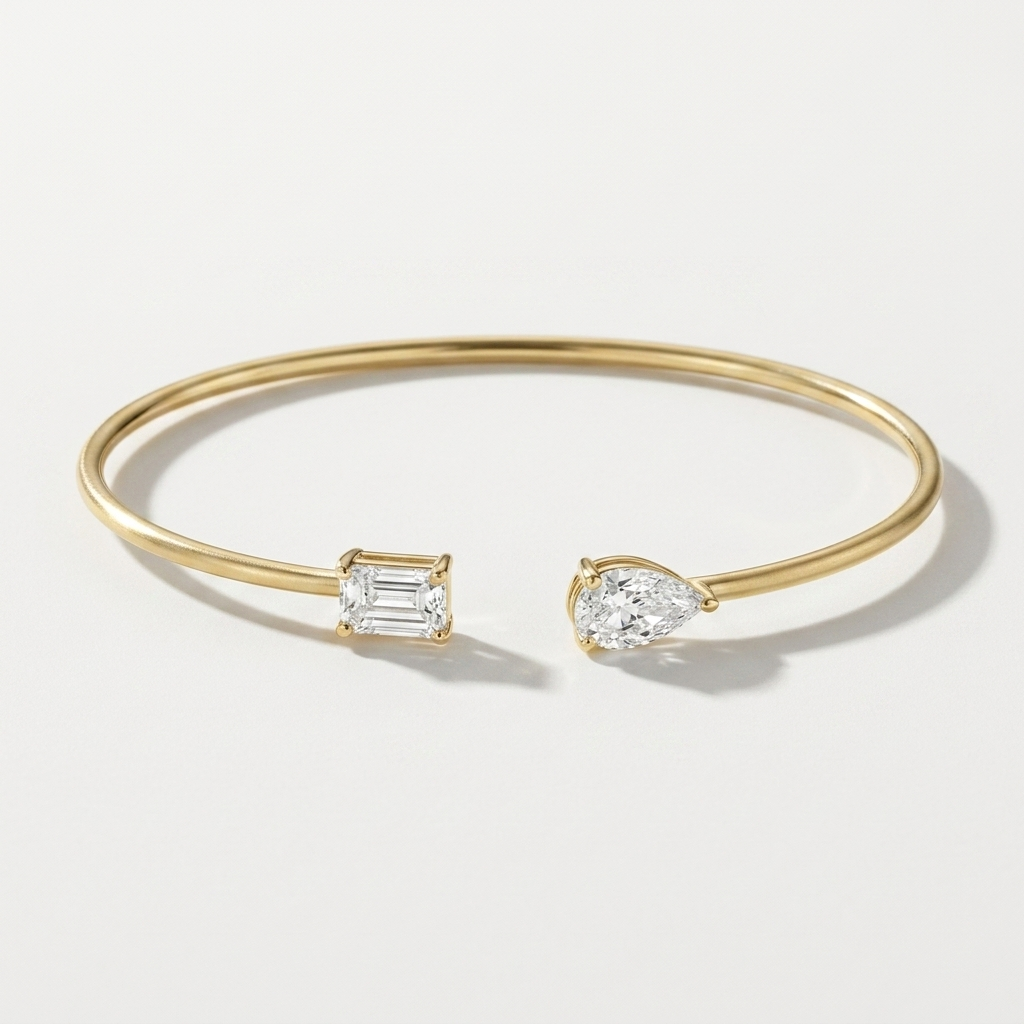 Refined pear-shaped lab grown emerald and diamond bangle in yellow gold, a sleek and sophisticated accessory for any occasion