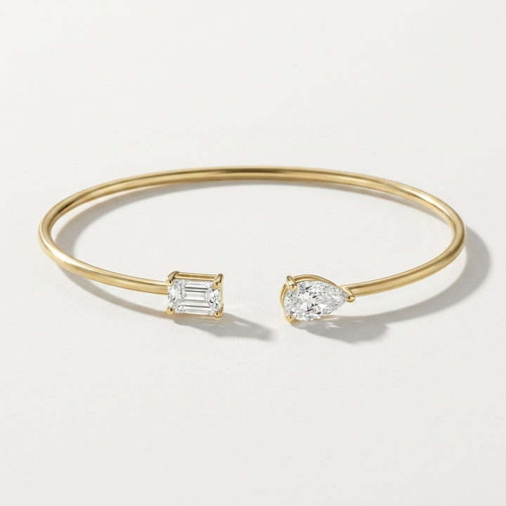 Refined pear-shaped lab grown emerald and diamond bangle in yellow gold, a sleek and sophisticated accessory for any occasion